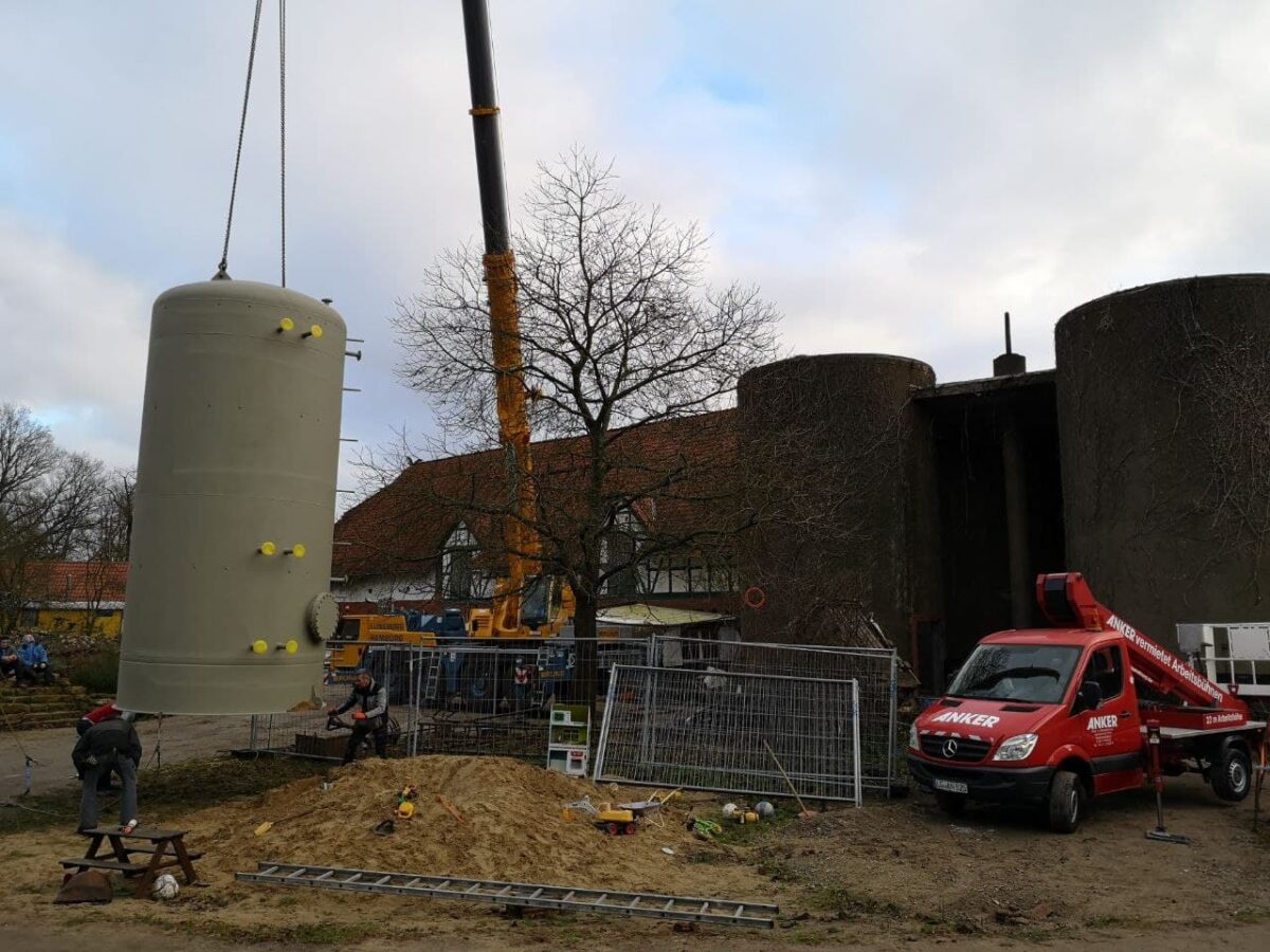 Mit einem Kran wird der Pufferspeicher in eines der hinteren Silos gehievt.