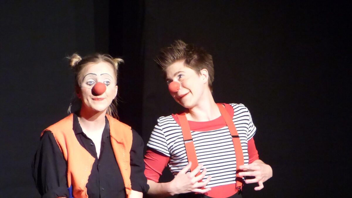 Zwei Clowns vor schwarzem Hintergrund.